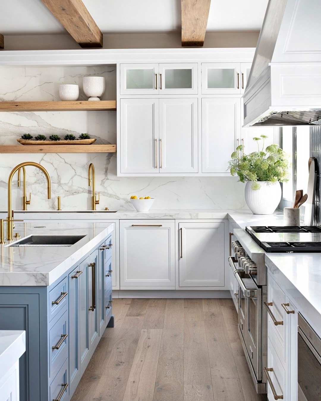 Crisp cool blue kitchen island with wood beams and marble backsplash, design by HW Interiors